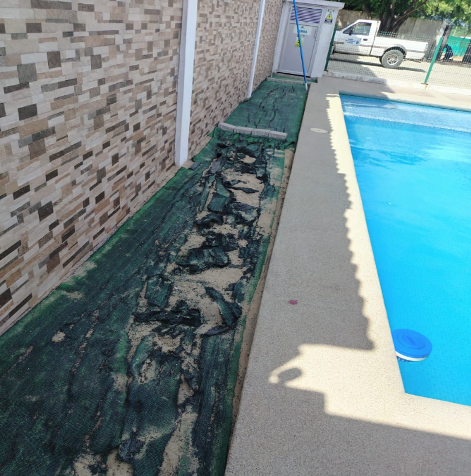 Césped en mal estado y con desgaste en el área de piscina.