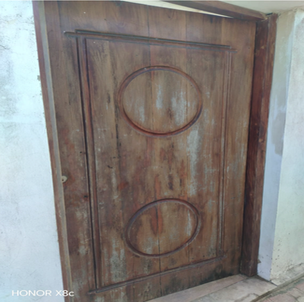 Puerta de salida hacia la playa con desgaste y deterioro en su pintura.